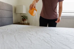 Application de bicarbonate de soude sur un matelas pour le nettoyage et la désodorisation à domicile.