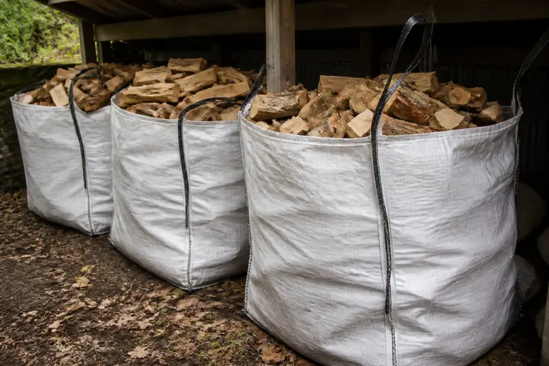 Stockage de plusieurs big bags pour bois de chauffage sous un abri extérieur