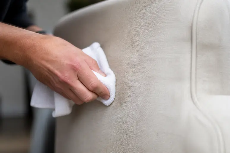 Test d'un chiffon légèrement humide sur le tissu délicat d'un canapé