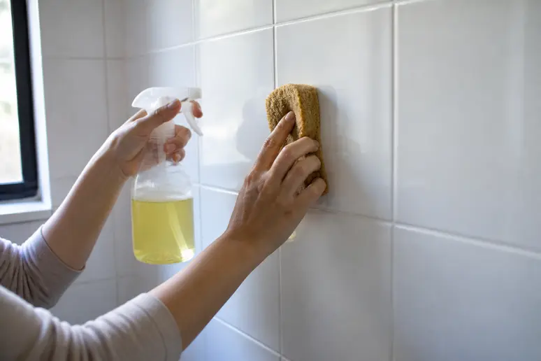 Application d'un produit nettoyant naturel sur un carrelage de salle de bain encrassé