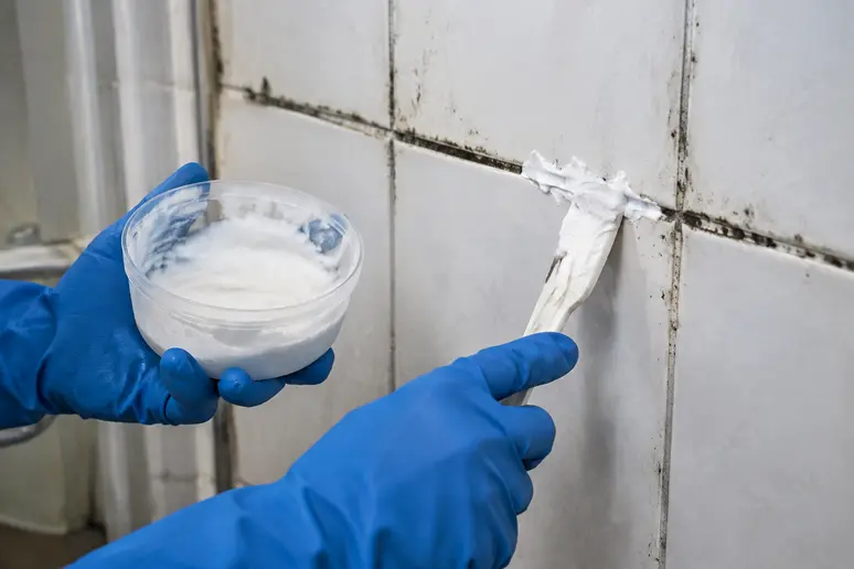 Application d'une pâte épaisse de bicarbonate sur les joints noircis du carrelage de douche