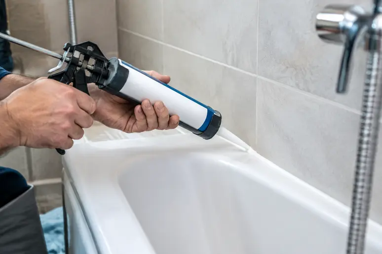 Pose d'un nouveau joint en silicone blanc avec un pistolet extrudeur