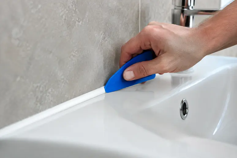 Lissage soigné d'un nouveau joint silicone pour garantir l'étanchéité du lavabo