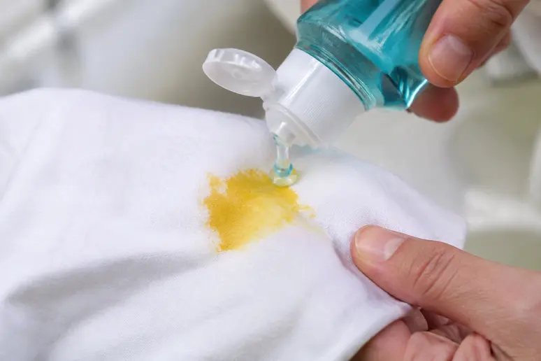Application de liquide vaisselle sur une tache de crème solaire incrustée dans un tissu blanc