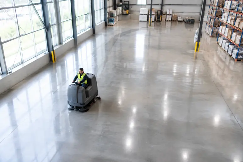 Autolaveuse professionnelle autoportée en service sur le sol d'un grand entrepôt lumineux
