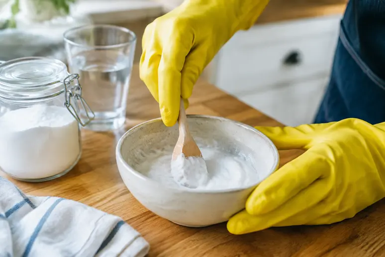 Mains préparant une pâte épaisse de bicarbonate de soude et d'eau dans un bol pour nettoyer son four
