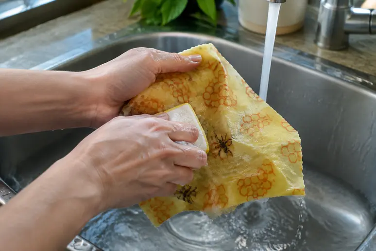 Nettoyage manuel d un tissu cire d abeille sous l eau tiede dans l evier de la cuisine