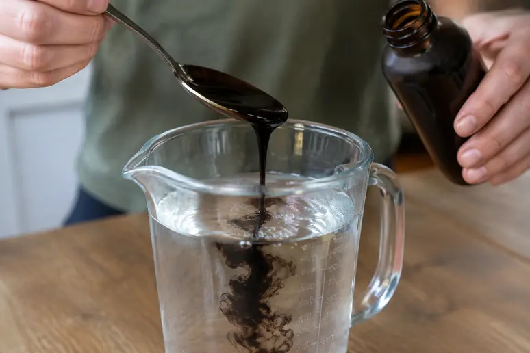 Dosage du savon noir liquide versé dans l'eau tiède pour préparer un traitement anti-pucerons