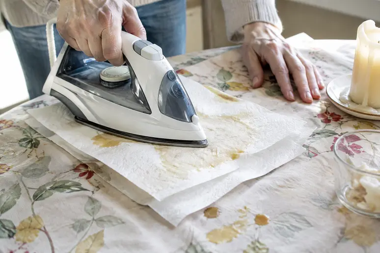 Repassage d'une nappe à travers du papier absorbant pour enlever une tache de bougie
