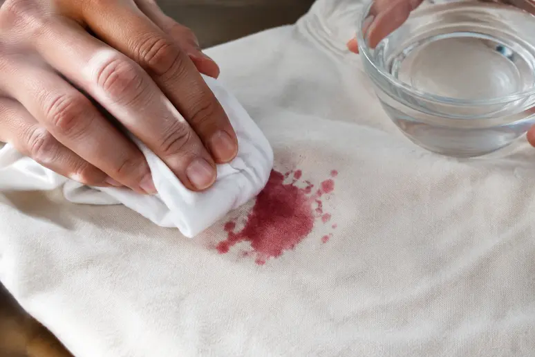 Tamponnement doux d'une tache de fruit rouge sur un vêtement avec un linge et du vinaigre blanc