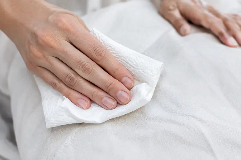 Tamponnement délicat d'une zone tachée sur un vêtement blanc en coton.