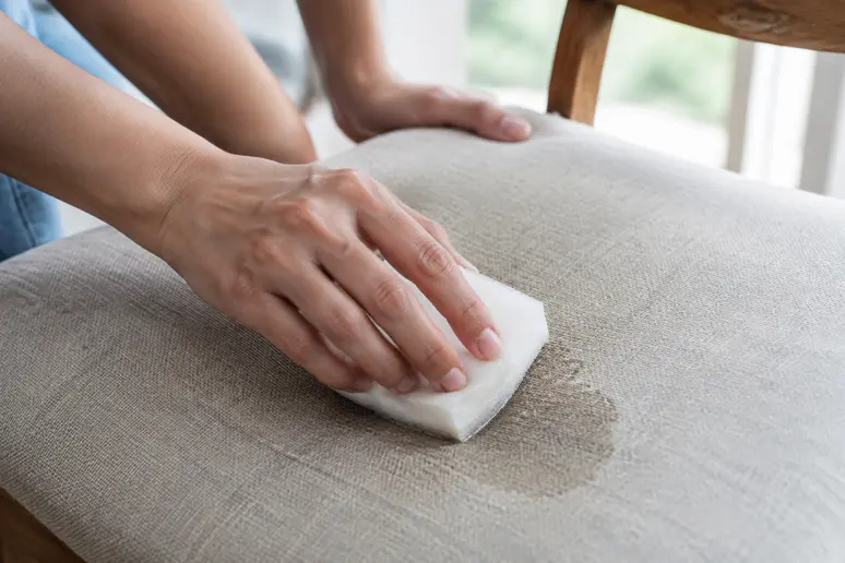 Tamponnage délicat d'une chaise en tissu avec une éponge essorée pour un nettoyage humide